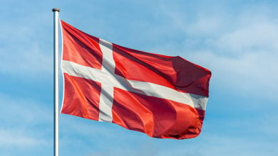 Closeup of single danish flag waving in the wind in front of blue sky