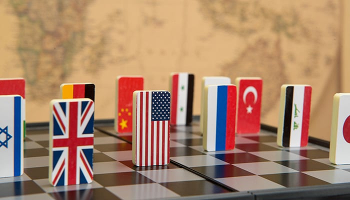 Symbols of countries on the chessboard against against the background the political map of the world. Conceptual photo, political games.