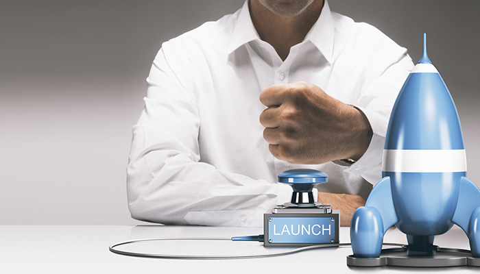 Man about to press a push button to launch a spaceship. Advertising concept of launching a new product or service. Composite between a 3D image and a photography background.