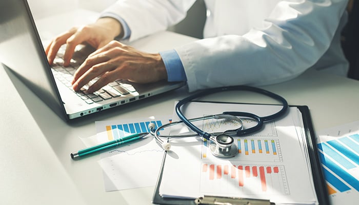 doctor working with medical statistics and financial reports in office