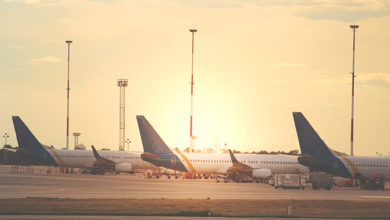 Busy working process at the airport. Horizontal shot of multiple passenger jet aircraft parked on the ramp at the airfield with evening sunlight of background.