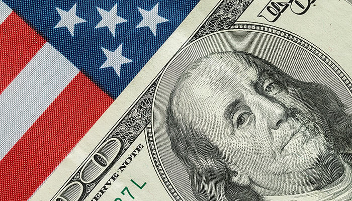 A hundred dollar bill in front of the American flag