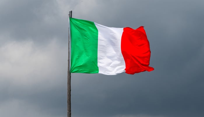 Italian flag against menacing dark storm clouds in the background