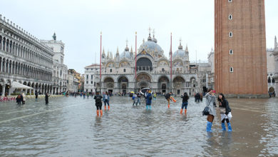 People walk on the catwalk in a flooded St. Mark's Square during a period of seasonal high water in Venice, Italy 10 November 2019