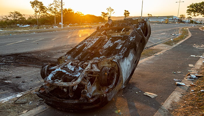 Durban, South Africa, 15 July 2021. The wreck of a destroyed car lies on a pavement, after being vandalized and set of fire during a violent protest in the area.