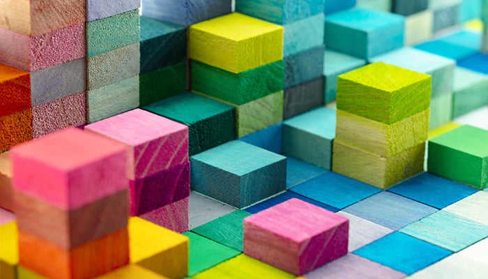 Spectrum of stacked multi-colored wooden blocks. Background or cover for something creative, diverse, expanding, rising or growing. shallow depth of field.