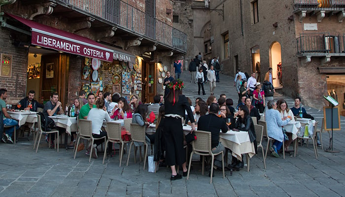 Siena, Italy, October 2 2017: People relaxing at the coffee shops in the streets of Siena historic town Italy, Europe