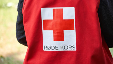 LYNGE, DENMARK - 23, JUNE 2016: The back of a Danish red cross worker in a red vest standing outside on a grrass field