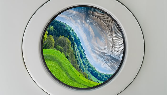 Concept symbol image greenwashing washing machine with deformed beautiful landscape inside