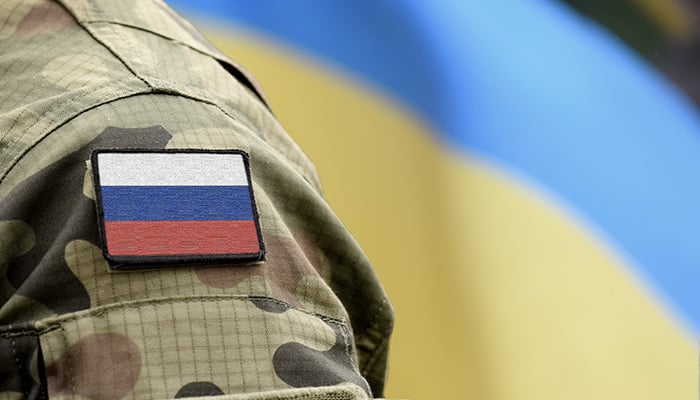 Flag of Russia on military uniform and flag of the Ukraine at background. Russia VS Ukraine.
