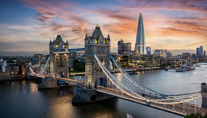 Aerial view to the illuminated Tower Bridge and skyline of London, UK, just after sunset