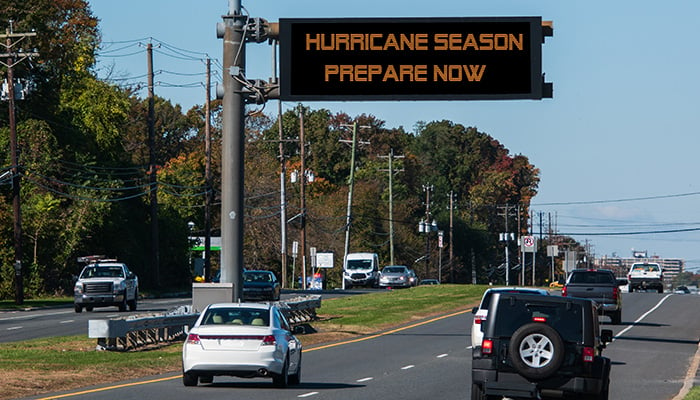 Digital electronic mobile road warning sign that says Hurricane Season prepare now, over a busy highway