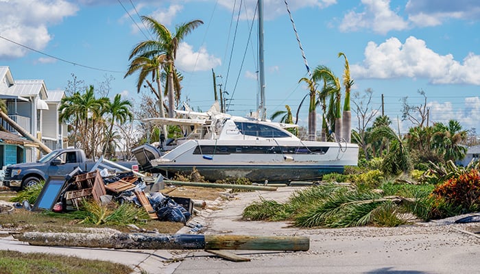 Image of a catamaran resting on a residential neighborhood street after Hurricane Ian Fort Myers FL