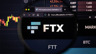 KAUFBEUREN, GERMANY - October 02, 2021. FTX company logo on a website with blurry stock market developments in the background, seen on a computer screen through a magnifying glass.