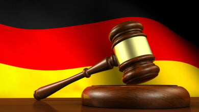 Germany laws, legal system and justice concept with a 3D rendering of a gavel and the German flag on background.