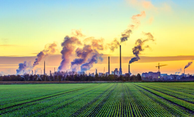 industry complex in Frankfurt in early morning with green fields and smoking chimney