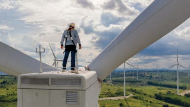 Windmill engineer wearing PPE standing on wind turbine