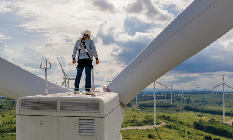 Windmill engineer wearing PPE standing on wind turbine