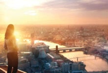 Woman high up on top of a building viewing a panorama of central London, including The Thames