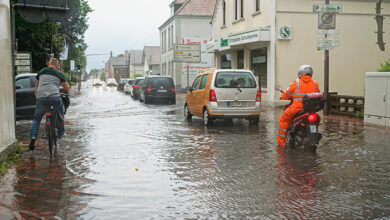 Brake, Germany - July 14, 2021: cars and a motorcycle stand in the street Kirchenstraße which has been overflooded after a heavy rainfall from Storm Bernd