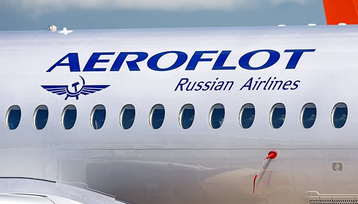 MOSCOW, RUSSIA - CIRCA JULY, 2017: Aeroflot Russian Airlines Sukhoi Superjet 100 twin jet engine passenger airplane side closeup fuselage view with aircraft windows logo lights landscape background
