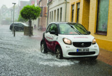 Brake, Germany - July 14, 2021: a car drives in the street "Schulstraße" through heavy rain, the street is flooded