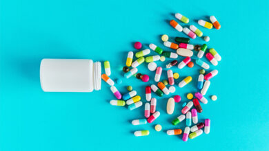 assortment of pharmaceutical medicine capsules, pills and tablets in bottle on blue background