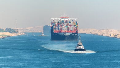 smailia, Egypt - November 5, 2017: Large container vessel ship MSC Maya passing Suez Canal in the sandy haze in Egypt. Tugboat accompanies the ships.